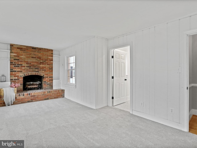 unfurnished living room featuring light colored carpet and a brick fireplace