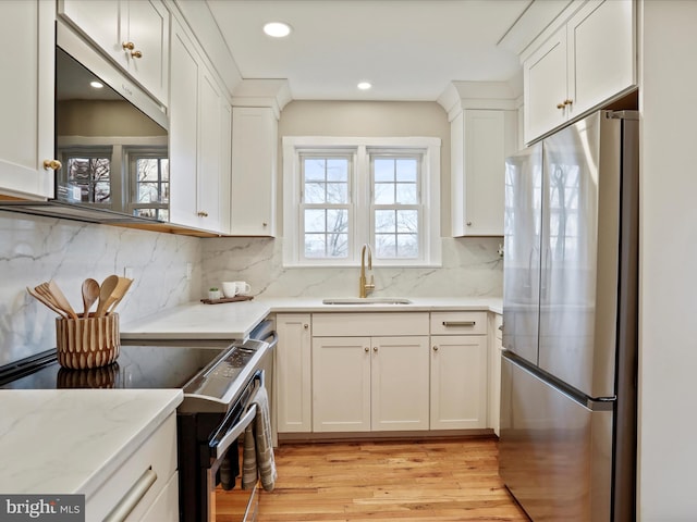 kitchen with electric range oven, fridge, and white cabinets