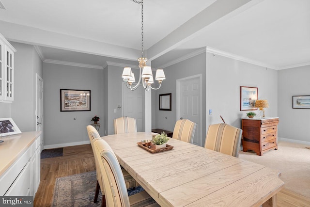 dining space featuring a raised ceiling, ornamental molding, a chandelier, and light hardwood / wood-style floors