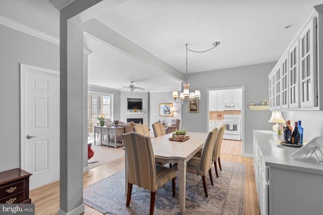 dining room with ornamental molding, ceiling fan with notable chandelier, and light wood-type flooring