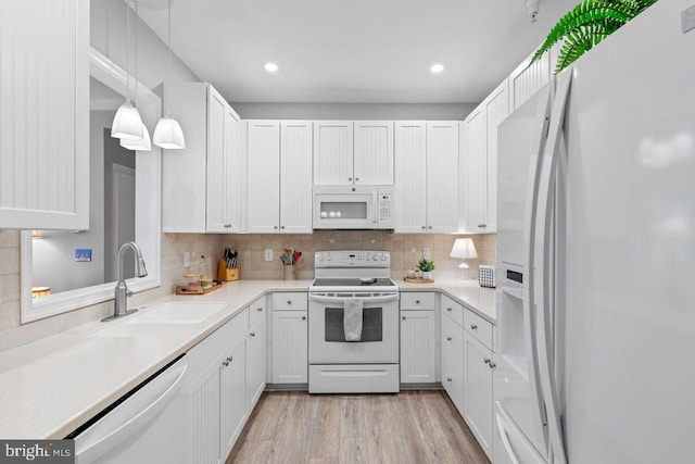 kitchen featuring sink, light hardwood / wood-style flooring, pendant lighting, white appliances, and white cabinets