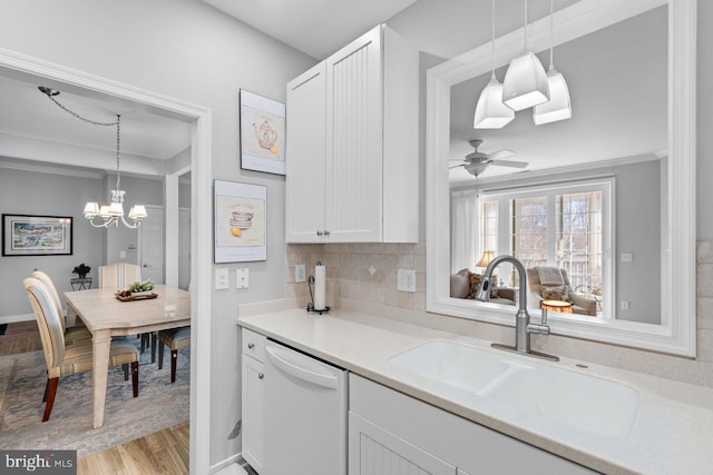 kitchen with sink, white dishwasher, white cabinets, decorative backsplash, and light wood-type flooring