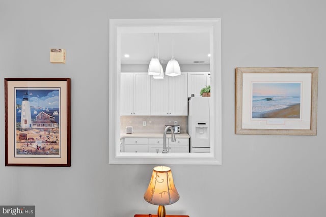 details featuring white refrigerator with ice dispenser, sink, and backsplash