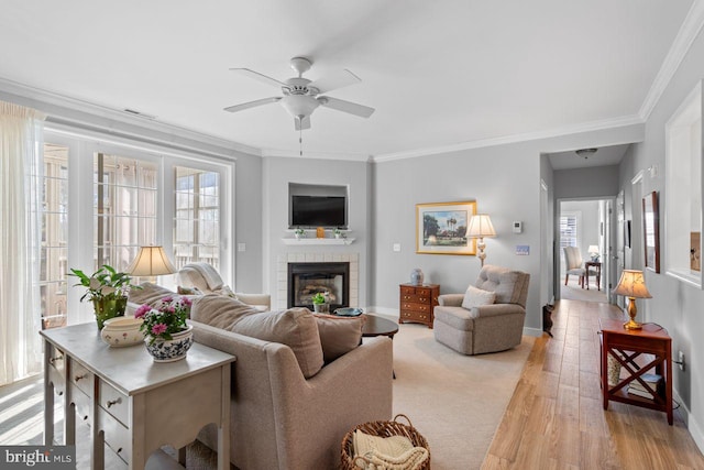 living room featuring crown molding, plenty of natural light, light hardwood / wood-style floors, and a brick fireplace