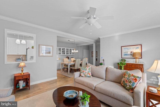 living room with ceiling fan with notable chandelier, light hardwood / wood-style flooring, and ornamental molding