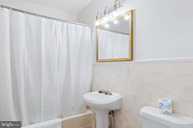 bathroom featuring toilet and tile walls