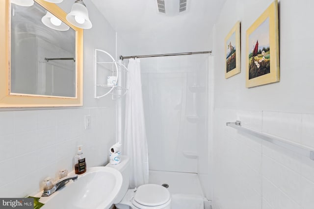 bathroom with tile walls, sink, and curtained shower