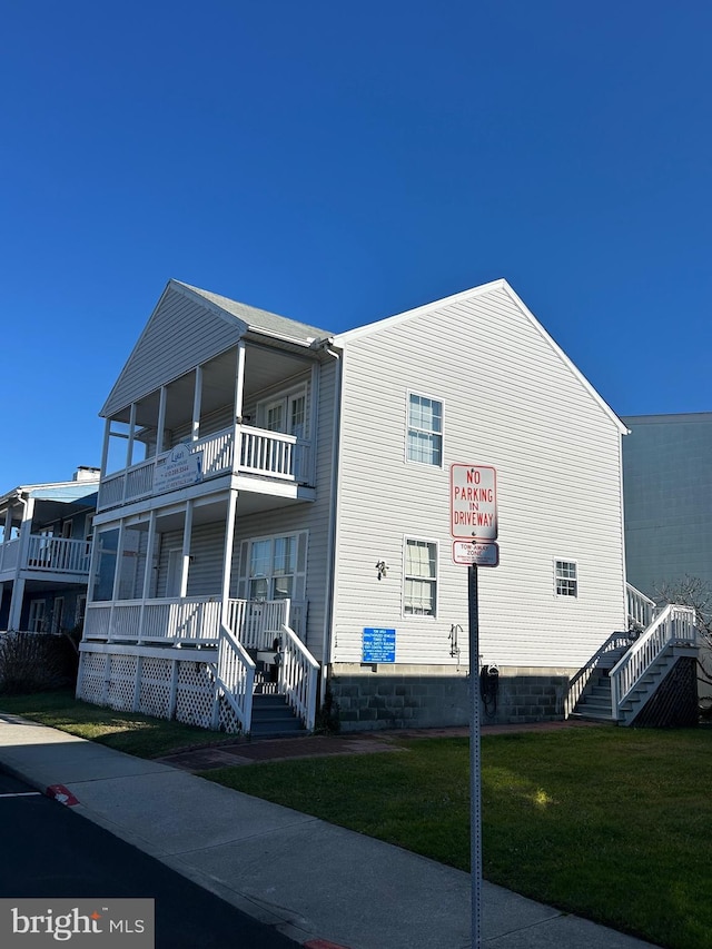 view of front of home with a front yard, a balcony, and a porch