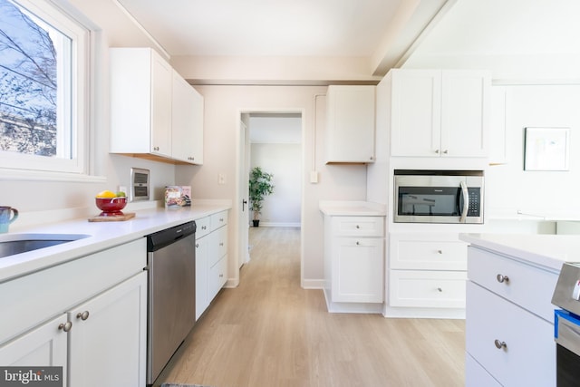 kitchen featuring stainless steel appliances, sink, white cabinets, and light hardwood / wood-style flooring