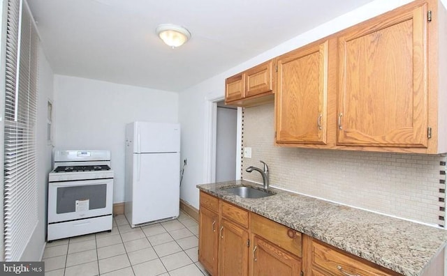 kitchen featuring light stone counters, sink, white appliances, and backsplash