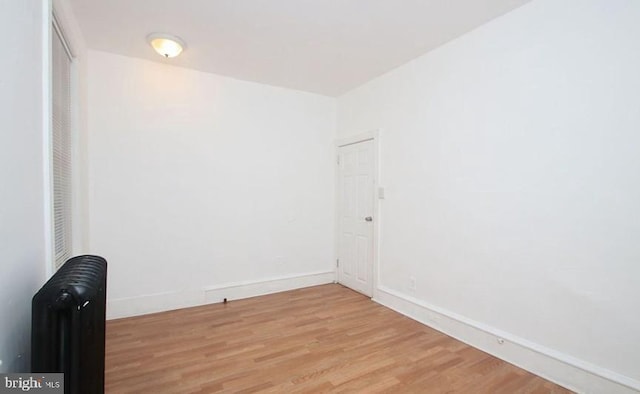 unfurnished room with light hardwood / wood-style flooring and radiator heating unit