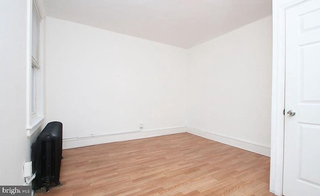 spare room with radiator heating unit and light hardwood / wood-style floors