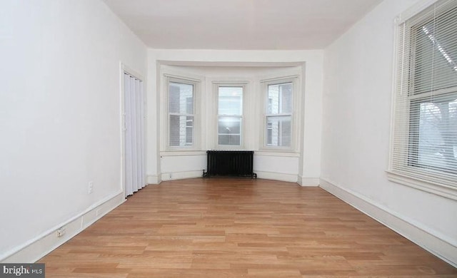 unfurnished living room featuring radiator and light wood-type flooring