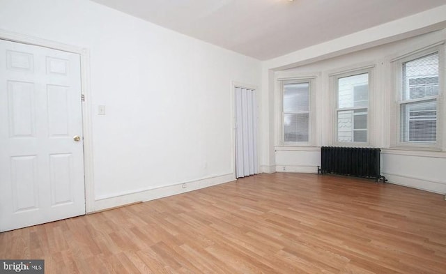 unfurnished living room with radiator heating unit and light wood-type flooring