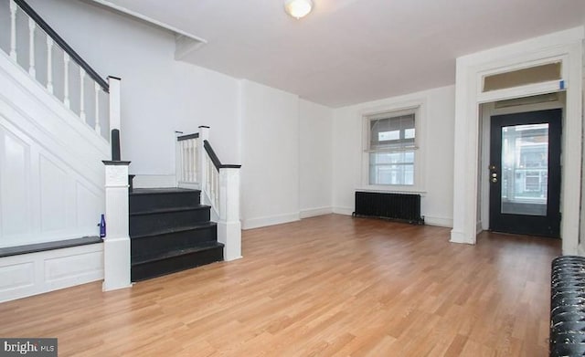 unfurnished living room featuring radiator heating unit and light hardwood / wood-style flooring