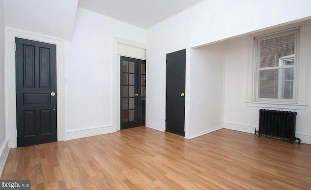 interior space featuring radiator heating unit and light wood-type flooring