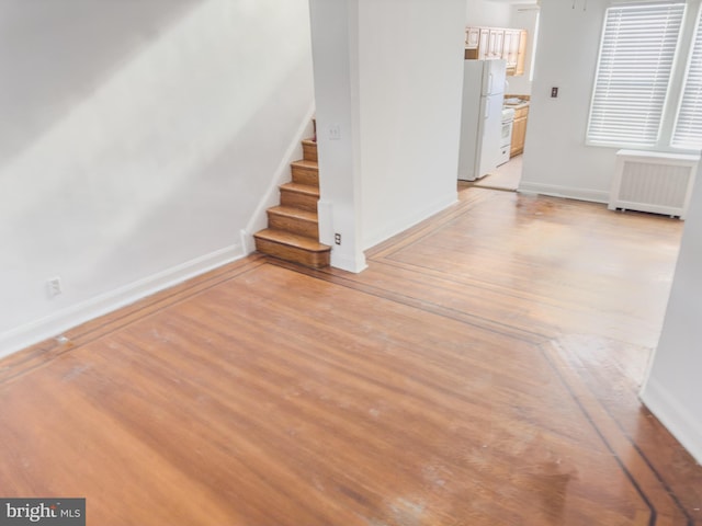 unfurnished living room featuring radiator and light hardwood / wood-style flooring