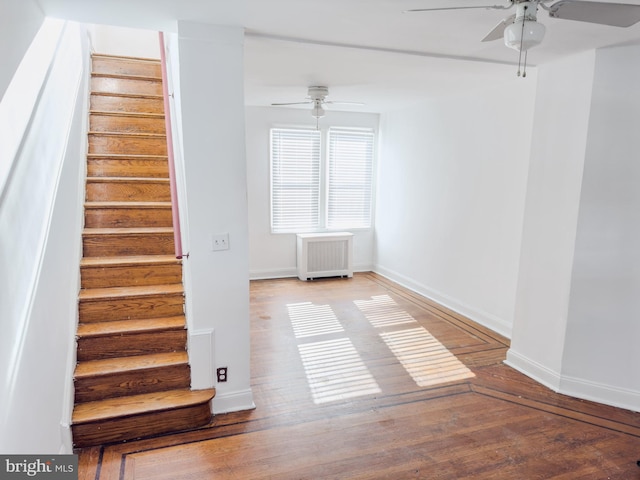 stairway with ceiling fan, radiator heating unit, and wood-type flooring