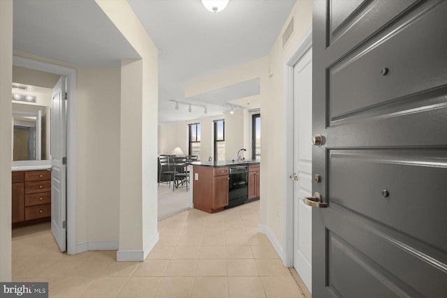 corridor featuring light tile patterned flooring, rail lighting, and sink