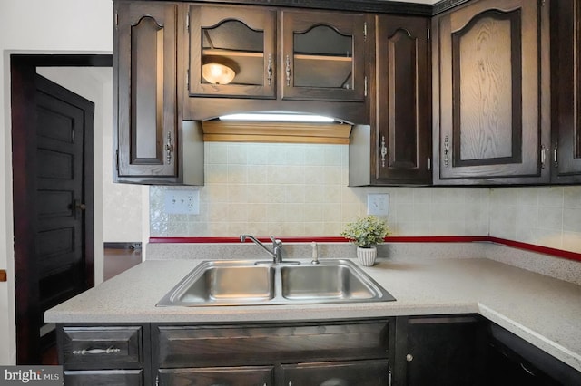 kitchen with tasteful backsplash, dark brown cabinets, and sink