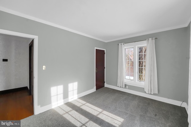 spare room with crown molding and dark colored carpet