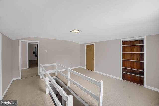 corridor with lofted ceiling, light carpet, and built in features