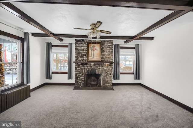 unfurnished living room with beamed ceiling, a stone fireplace, radiator, and light carpet