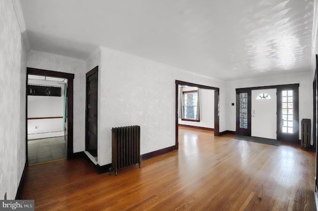 foyer entrance with radiator, hardwood / wood-style flooring, plenty of natural light, and a baseboard heating unit