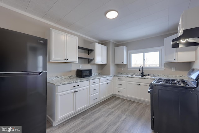 kitchen with sink, white cabinets, light stone counters, black appliances, and light wood-type flooring