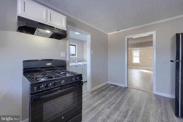 kitchen featuring crown molding, black appliances, light hardwood / wood-style flooring, washer and clothes dryer, and white cabinets