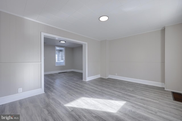 empty room with ornamental molding and light wood-type flooring