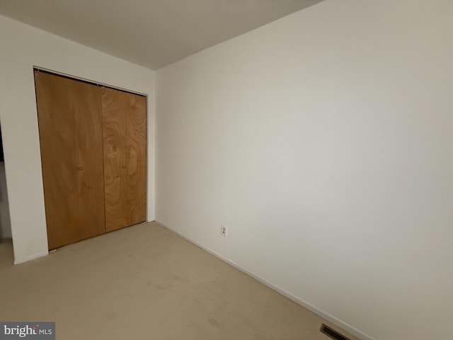 unfurnished bedroom with light carpet and a closet