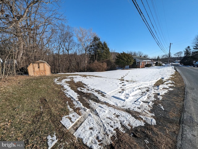 snowy yard featuring a storage unit