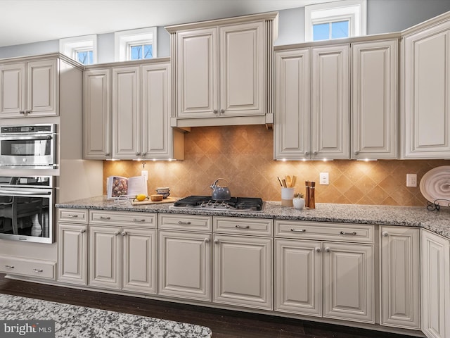 kitchen featuring backsplash, light stone countertops, and appliances with stainless steel finishes