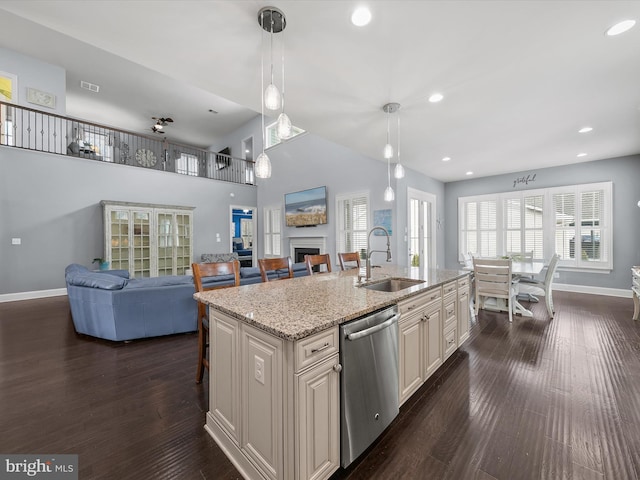 kitchen featuring a breakfast bar, sink, stainless steel dishwasher, pendant lighting, and a kitchen island with sink