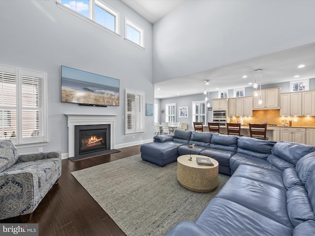 living room with dark hardwood / wood-style floors and a towering ceiling