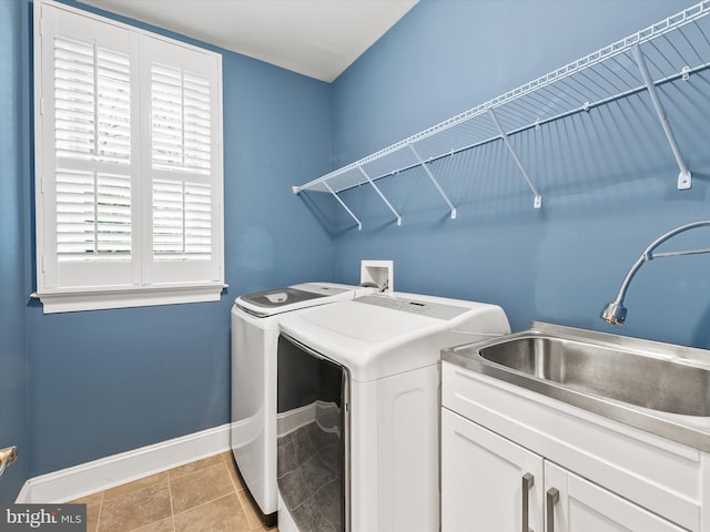 clothes washing area featuring sink, light tile patterned floors, cabinets, and washer and dryer