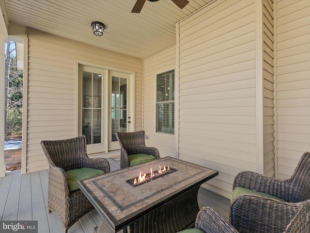 wooden terrace featuring ceiling fan and a fire pit