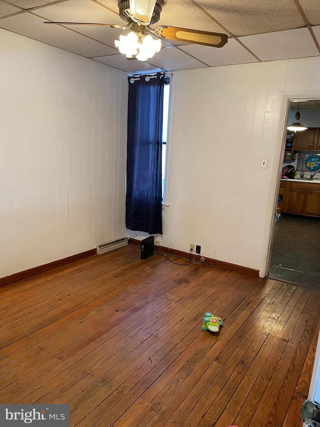 spare room with ceiling fan, hardwood / wood-style floors, and a drop ceiling