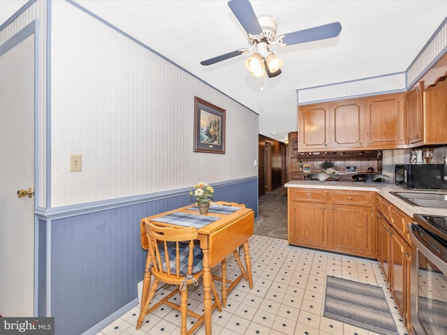 kitchen with a sink, light floors, black microwave, and electric stove