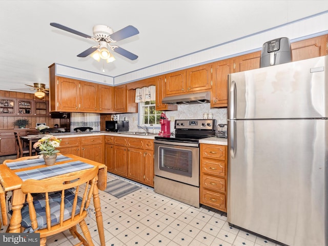 kitchen with light floors, stainless steel appliances, light countertops, backsplash, and under cabinet range hood