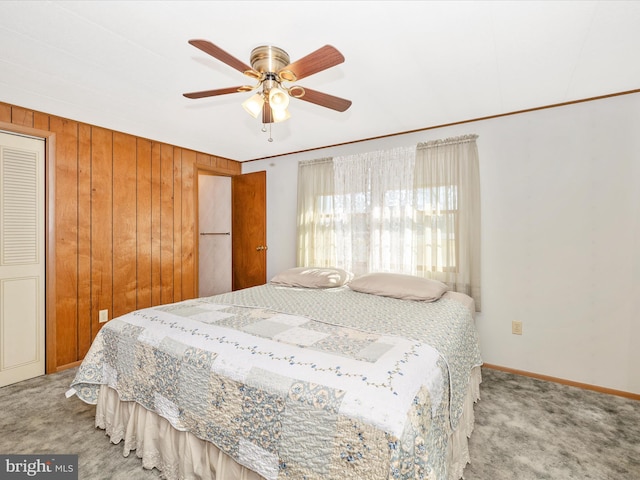 bedroom with wooden walls, a ceiling fan, baseboards, a closet, and carpet