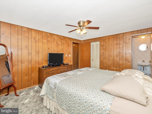 carpeted bedroom featuring a sink, wood walls, and a ceiling fan