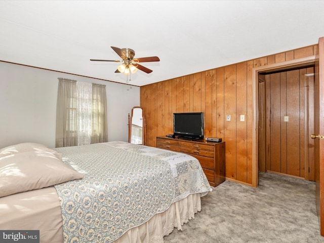 bedroom with light carpet, ceiling fan, and wooden walls