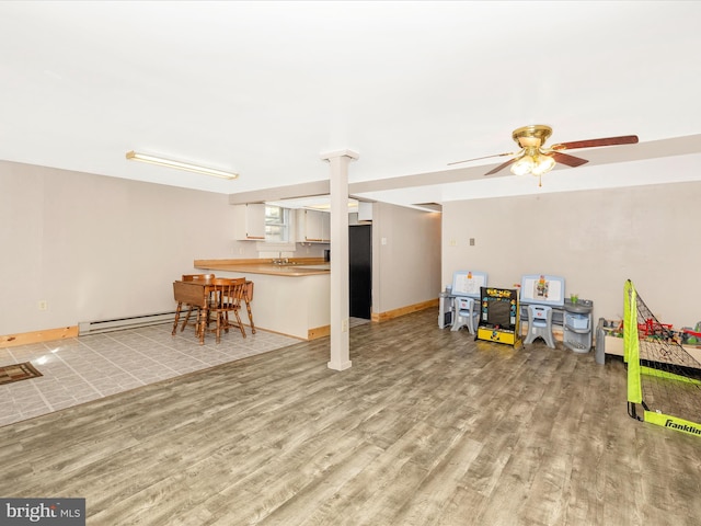 living room featuring a baseboard heating unit, baseboards, light wood finished floors, and a ceiling fan