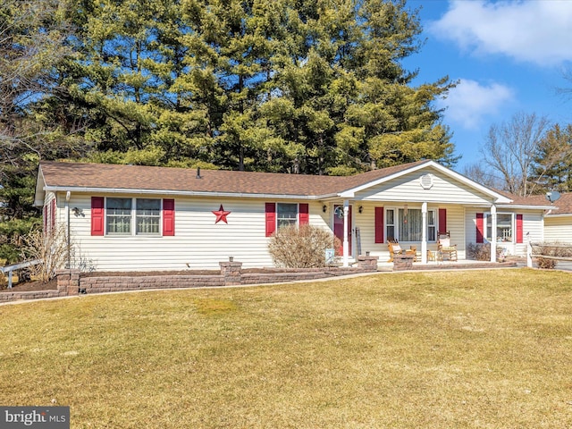 ranch-style house featuring covered porch and a front lawn