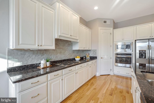 kitchen featuring white cabinetry, stainless steel appliances, and dark stone counters