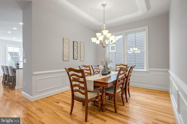 dining area featuring a chandelier, crown molding, a raised ceiling, and light hardwood / wood-style flooring