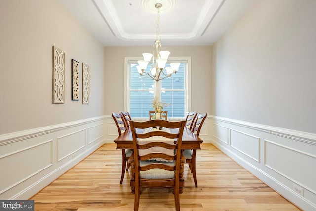 dining room featuring an inviting chandelier, a tray ceiling, and light hardwood / wood-style floors