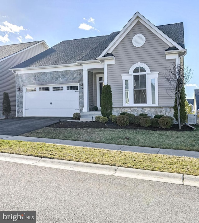 view of front facade with a garage, central AC, and a front lawn